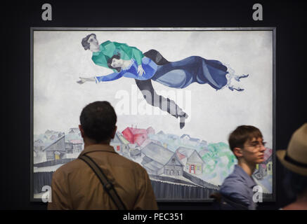 Visiteurs en face de la peinture 'sur la ville' par peintre moderniste russe Marc Chagall (1914-1918) présentés à l'exposition au Centre Pompidou à Paris, France. L'exposition consacrée à l'avant-garde russe dans la région de Vitebsk (1918-1922) s'étend jusqu'au 16 juillet 2018. Banque D'Images