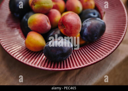 Close up d'abricots mûrs et les prunes sur la plaque sur la table Banque D'Images