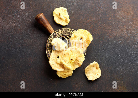 Anneaux d'ananas confits séché. Tranches de fruits doux sur fond de béton brun. Vue d'en haut. Banque D'Images