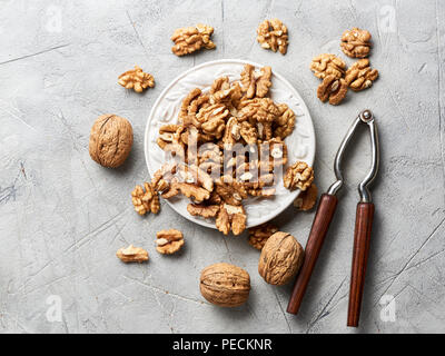 Les cerneaux de noix sur la plaque blanche sur fond gris avec Casse-noisette. Banque D'Images