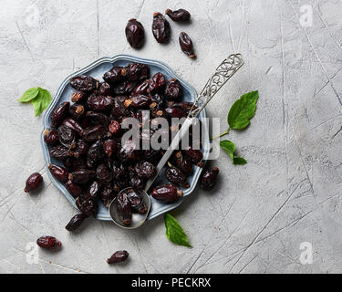 Rose musquée séchés avec des feuilles vertes sur plaque sur fond noir. Banque D'Images