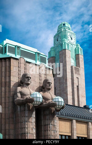 La gare centrale de Helsinki avec deux hommes de pierre statues holding lampes et la gare la tour de l'horloge. Banque D'Images