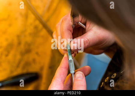 Travailler avec une pince sur un bijou à l'atelier à l'aide du matériel adapté et goldsmith debout et tenant avec les deux mains Banque D'Images