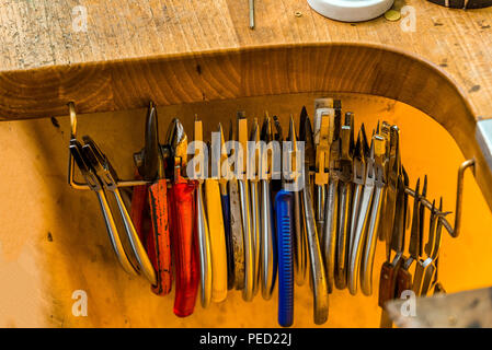 L'équipement et des outils d'un orfèvre avec pinces et pinces et tenailles suspendue à un bureau de travail en bois à l'intérieur d'un atelier Banque D'Images