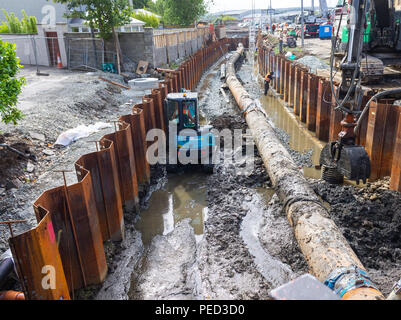 Mini digger travaillant sur une tranchée d'excavation près d'un pipe-line à côté de coffrage métallique. Banque D'Images