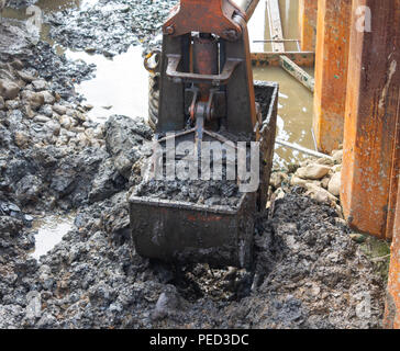 Mechanical digger avec godet creuser une tranchée sur un chantier de construction. Banque D'Images
