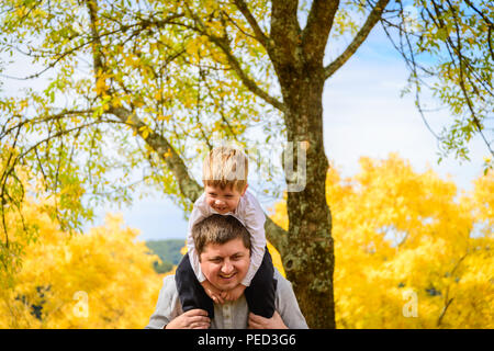 Père de donner son fils piggyback ride in autumn park, Adelaide Hills, Australie du Sud Banque D'Images