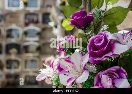 Bouquet de fleurs artificielles violet contre l'enterrement au cimetière de niches de Poblenou à Barcelone, Espagne. Banque D'Images