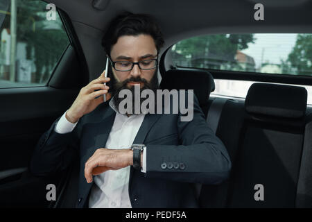 Un homme d'affaires tout en voyageant en voiture sur le siège arrière à l'aide d'un sm Banque D'Images