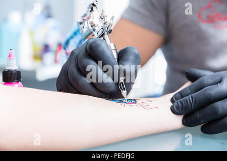 Close-up de la main d'un tatoueur qualifiés portant des gants noir Banque D'Images