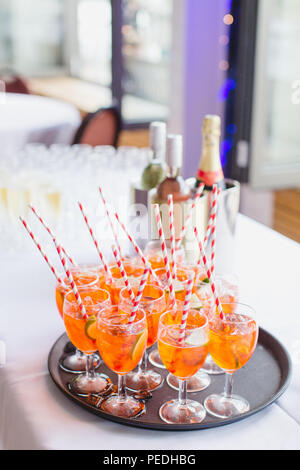 Un bac d'Aperol Aperol. Sprtiz (cocktails Xavier et l'eau gazeuse) avec du papier à rayures rouges et blanches de pailles Banque D'Images