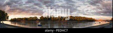 Vue panoramique sur la Tamise à Putney à vers Fulham (Bishop's Park) avec un bateau d'aviron rameurs dans la distance. Le coucher du soleil. Big Sky. Nuages Banque D'Images