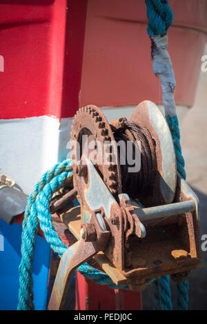 Un treuil de la remorque d'un rouge, blanc et bleu bateau de pêche peint Banque D'Images