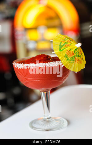 Boisson glacée rouge avec parapluie cocktail devant un juke-box Banque D'Images