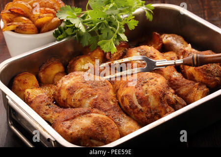 Cuisses de poulet rôti avec des pommes de terre frites sur fond de bois Banque D'Images