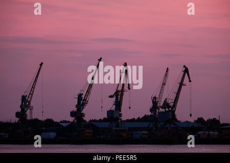 Silhouettes de grues de quai en face de Sunset Sky Banque D'Images