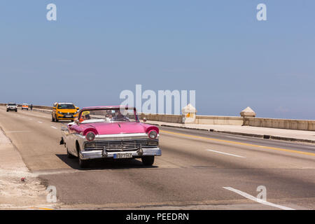 Convertible rose American Classic vintage car la conduite sur le Malecon au soleil d'été, La Havane, Cuba Banque D'Images