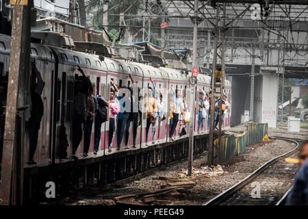 Les passagers des trains de banlieue de Mumbai porte sur un train de chemin de fer à la gare de Bandra à Mumbai, Inde Banque D'Images