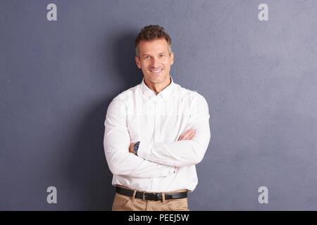Portrait of businessman wearing shirt debout les bras croisés au fond gris. Banque D'Images
