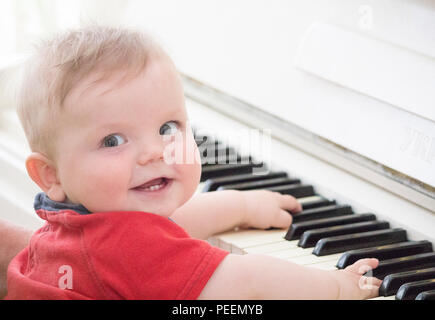 Bébé au piano joue dans un T-shirt rouge Banque D'Images