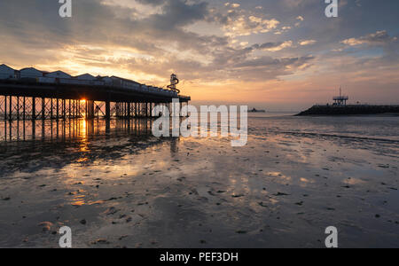 Coucher de soleil derrière Herne Bay, une ville balnéaire sur la côte du Kent, à l'ancienne jetée tête et bras de Neptune sur la droite. Banque D'Images