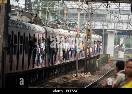 Les passagers des trains de banlieue de Mumbai porte sur un train de chemin de fer à la gare de Bandra à Mumbai, Inde Banque D'Images