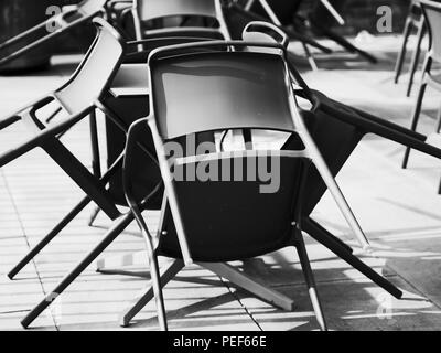 Résumé image noir et blanc de chaises entassées étrangement sur une terrasse dans une journée ensoleillée. Banque D'Images