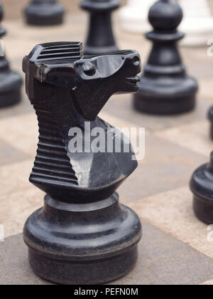 Close-up de grandes pièces des échecs à un jardin. L'accent sur le chevalier noir au premier plan. Le format Portrait. Banque D'Images