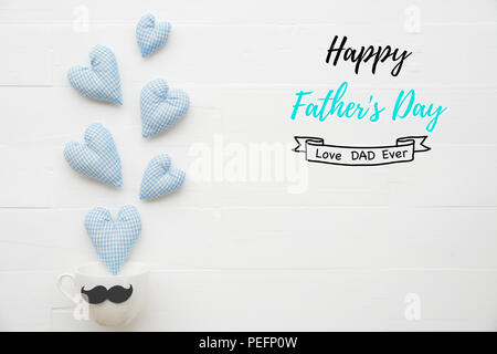 Heureux pères jours concept. Vue de dessus du coeur bleu fait main splash out à partir de la tasse de café avec une moustache noire sur table en bois pastel blanc brillant backgrou Banque D'Images