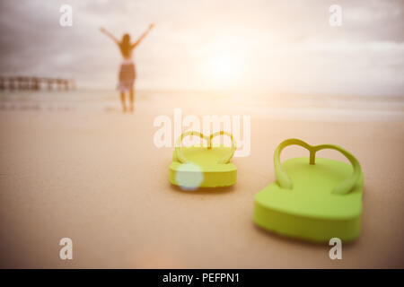 Soft focus on Green flip flop avec happy woman bras ouverts sur la plage de sable fin pour des vacances d'été et de vacances. Banque D'Images