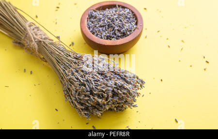 Concept d'herbes. Vue de dessus de lavande séchées bouquet sur table et fond jaune dans bol en bois. Banque D'Images