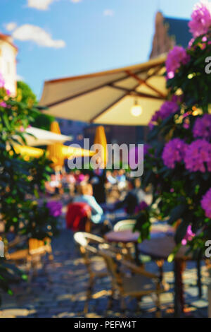 Café en plein air avec de belles fleurs et de parapluies dans la vieille ville. Flou Banque D'Images