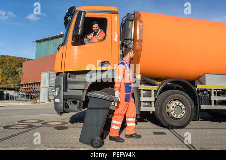 Deux garbagemen travaillant ensemble sur le vidage de poubelles Banque D'Images