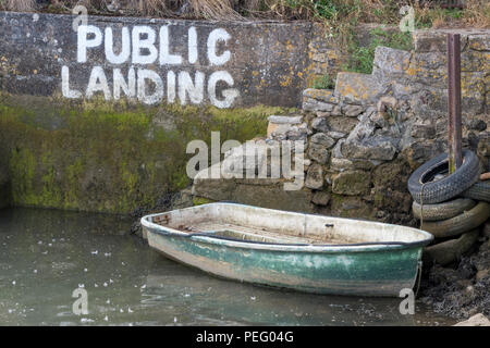 Un petit bateau à rames débraillés ou canot amarré à côté d'un ensemble d'étapes d'atterrissage à marée basse. Banque D'Images