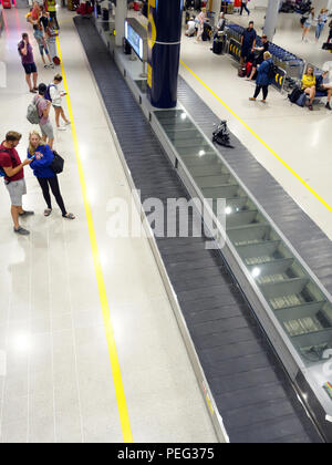 Les voyageurs qui attendent le tapis de transport numéro 6 du terminal 3 du hall des arrivées de l'aéroport international de Manchester Banque D'Images