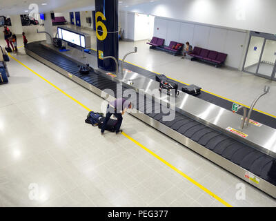 Voyageur masculin en attente du tapis de transport de collecte numéro 6 dans le terminal 3 du hall des arrivées de l'aéroport international de Manchester Banque D'Images