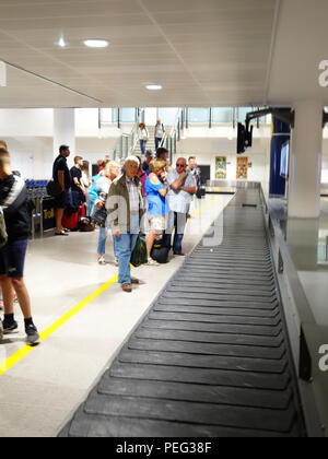 Les voyageurs qui attendent le tapis de transport numéro 6 du terminal 3 du hall des arrivées de l'aéroport international de Manchester Banque D'Images