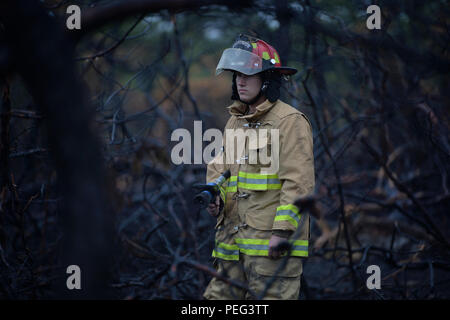 Airman Senior Brandon L. Ehlers, un pompier avec la 106e Escadre de sauvetage, d'aérosols dans une zone de forêt brûlée avec de l'eau le 21 août 2015. Plusieurs organismes et services d'incendie ont répondu à une grande brousse dans ce domaine. Les pompiers du 106e s'est rendue à vérifier pour les points d'une grave préoccupation, étant donné le temps sec autrement au cours de la semaine dernière. L'incendie a détruit quatre acres une large bande de terrain à l'extérieur FS Gabreski ANG juste à côté de l'ancienne route de Riverhead, exigeant une réponse multi-agences, y compris huit camions-citernes pinceau, sept et quatorze ministères différents qui travaillent ensemble. (New York Banque D'Images