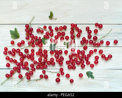 Les grandes baies de groseille rouge sont dispersées sur un fond de bois ensemble avec des feuilles vertes sont retirés de close-up ci-dessus Banque D'Images