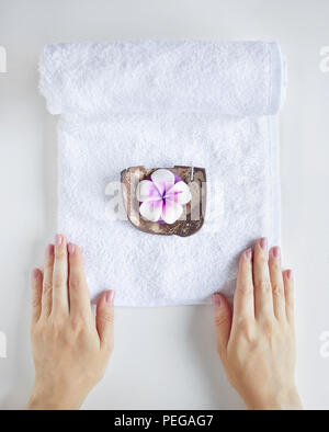 Spa et le traitement. Femme tenant une serviette blanche avec bougie violet sur fond uni blanc Banque D'Images