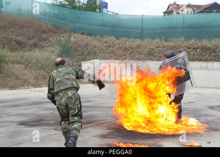 Un instructeur de phobie du feu de l'armée portugaise dirige un entraînement au cocktail Molotov pour les soldats hongrois du 5e Bocskai Istvan affectés au groupement tactique multinational est au Camp Slim Lines, au Kosovo, le 12 août 2015. L’exercice, qui fait partie de la mission de soutien de la paix de l’OTAN, teste les réactions des soldats aux risques d’incendie et au contrôle des foules tout en assurant la sécurité et la disponibilité opérationnelle dans les opérations du poste de commandement avancé. Banque D'Images