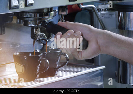 Close up sur les mains faire deux tasses de café espresso sur une machine Banque D'Images