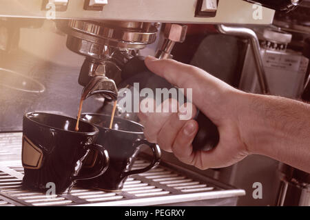 Close up sur les mains faire deux tasses de café espresso sur une machine Banque D'Images