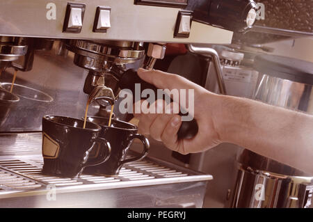 Close up sur les mains faire deux tasses de café espresso sur une machine Banque D'Images