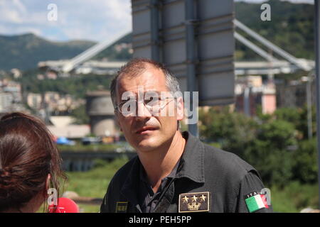 Gênes, Italie. Août 15, 2018. Fireman Emanuele Gissi répond aux questions des journalistes. Un jour après l'effondrement de l'autoroute pont Morandi (arrière-plan), il est toujours recherché pour les survivants dans les ruines énormes. Credit : Fabian Nitschmann/dpa/Alamy Live News Banque D'Images