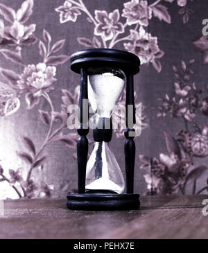 Hourglass avec du sable blanc sur une table en bois. Banque D'Images