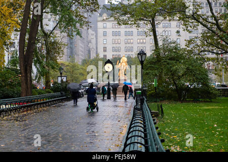 Personnes marchant sous la pluie vers l'installation de l'horloge en rotation par Alicja Kwade à Grand Army Plaza de Central Park, New York Banque D'Images