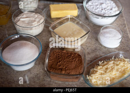 Pots avec ingrédients pour gâteau, lait concentré, beurre, cacao, chocolat, crème sure, fromage, sucre Banque D'Images