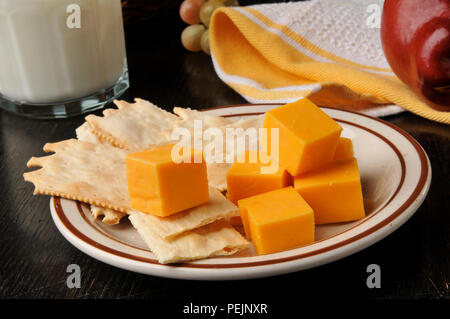 Pain plat gastronomique des craquelins avec du fromage cheddar fort, une pomme et du lait Banque D'Images