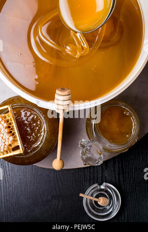 Le miel en pot et grand seau, honeycomb et bâton en bois, métal louche Banque D'Images